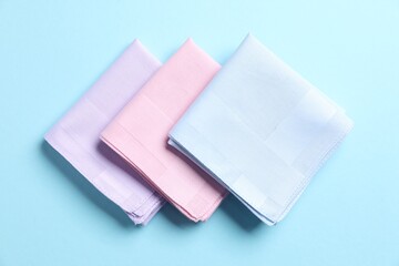 Different pastel color handkerchiefs on light blue background, flat lay