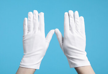 Woman in cloth gloves on light blue background, closeup