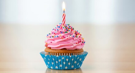 Single cupcake with pink frosting and lit candle on table