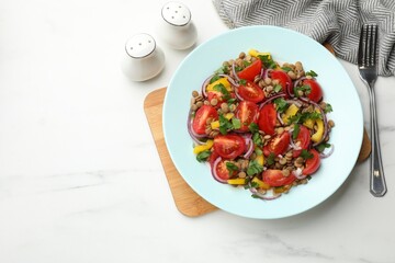 Delicious salad with lentils and vegetables served on white marble table, flat lay. Space for text