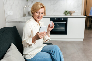 Mature woman checking medication details on her phone while smiling at home