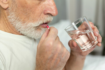 Senior man takes medication for mental health in home environment