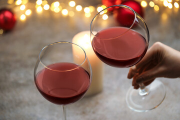 Woman with glass of red wine at gray table, closeup. Christmas and New Year celebration