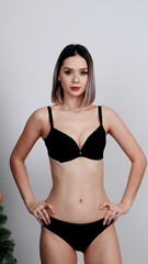 Fototapeta premium Confident woman in black bra and panties poses with hands on hips