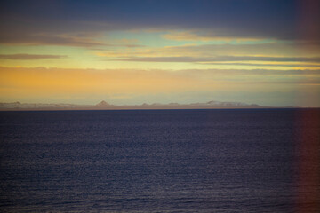 Fototapeta premium Calm sea and distant mountains at sunset