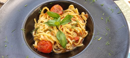 Delicious plate of pasta with cherry tomatoes and fresh basil served in an elegant setting