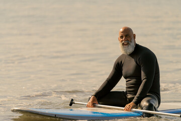 Mature man paddle boarding on ocean water