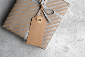 Blank gift tag mockup with copy space for design, featuring a beautifully wrapped present in brown paper with silver stripes and a decorative ribbon
