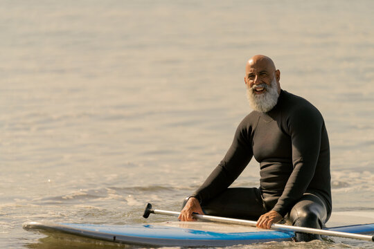 Mature man paddle boarding on ocean water