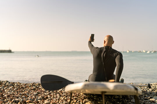 Man paddleboarding taking selfie on beach
