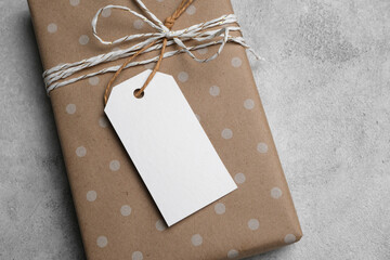 Brown gift box wrapped in dotted paper with twine and a blank tag, perfect for personalizing presents, showcasing thoughtful gifting ideas and creative packaging mockup
