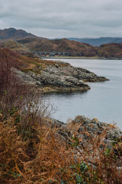 A striking photograph of the Loch nan Uamh Viaduct, located between Lochailort and Arisaig in the Scottish Highlands. The image highlights the impressive engineering of this multi-arch concrete struct