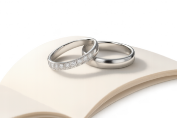 Elegant diamond and plain wedding rings on an open book, isolated transparent background