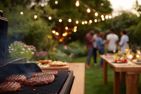 Group of friends gather around a barbecue grill, enjoying food and drinks in a vibrant garden - Powered by Adobe