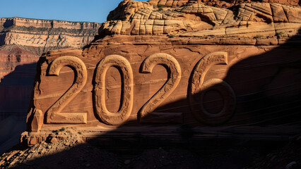 Large numbers 2026 carved into sandstone rock formation in a desert landscape during golden hour sunlight