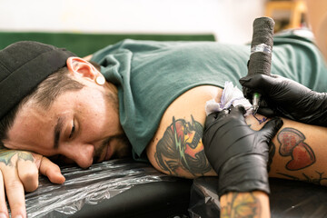 Tattoo artist creating design on man's arm