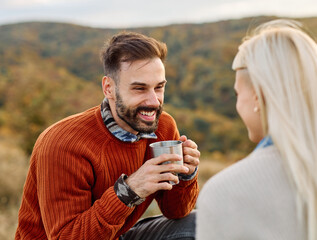 Hiking couple  enjoys nature  taking a break with water bottle or hot drink tea at the table  in a lush forest during a sunny day