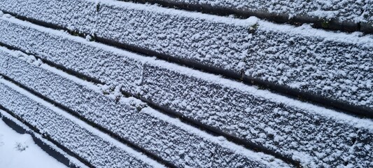 Snow covers concrete wall on a cold winter day, creating a serene blanket of white in a quiet outdoor setting