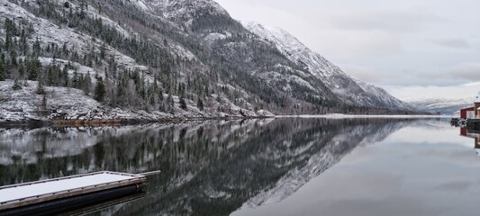Calm winter morning by the tranquil lake surrounded by snow-covered mountains in a remote location