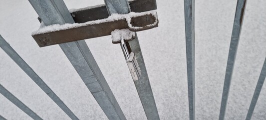 Winter gate securely locked in snowy surroundings on a cold day close to dusk