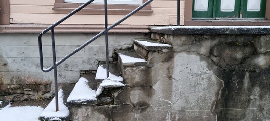 Snow-covered steps leading to a house entrance with a metal railing in a winter setting