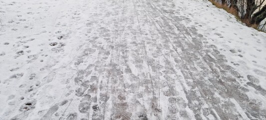 Snow-covered path shows evidence of footsteps in a serene winter landscape during the early morning