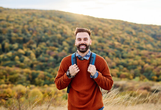 Hiking man enjoys nature with trekking backpack in a lush forest during a sunny day