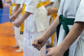 A line of children in white karate uniforms with yellow and green belts