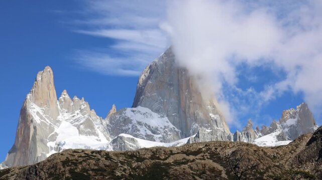Fitzroy mountain in Patagonia with sharp granite peaks rugged terrain drifting clouds clear sky remote wilderness glacial valley rocky landscape natural environment and panoramic daylight view scenery