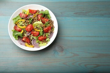 Delicious salad with lentils and vegetables on light blue wooden table, top view. Space for text