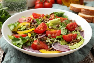 Delicious salad with lentils and vegetables on wooden table, closeup