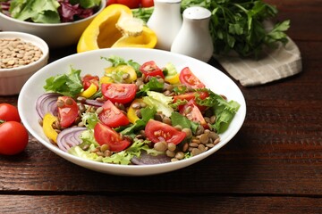 Delicious lentil salad and ingredients on wooden table, closeup