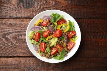 Delicious salad with lentils and vegetables on wooden table, top view