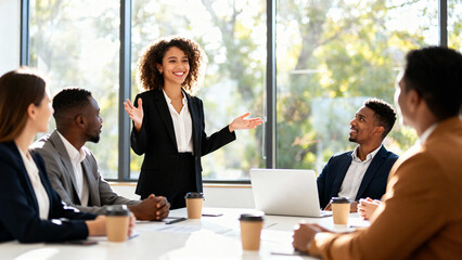 Smiling female leader presenting ideas to a diverse team of colleagues during a collaborative business meeting in a modern office
