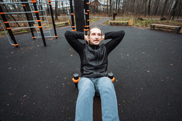 outdoor fitness demonstration, casual male exercises on bench beneath cloudy autumn sky, individual practicing bodyweight exercises outdoors at urban fitness park during fall conditions