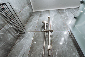 elegant marble fixture, sleek metallic components paired with polished gray stone background, contemporary bathroom fixture featuring functional handle against refined marble wall surface