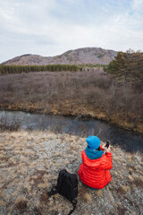Nature photographer capturing scenery, Explorer documenting river bend and hillside with camera equipment, Creative outdoor photographer capturing reflective water and mountain scenery