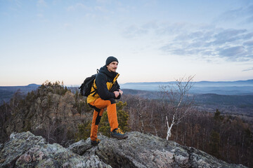 Adventurer surveys scenic mountain landscape, Hiker stands atop rugged summit at dawn, Backpacker captures breathtaking wilderness panorama while preparing for outdoor navigation practice