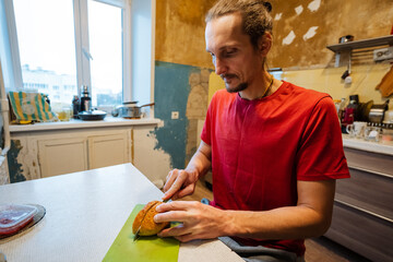 man preparing pumpkin, urban home cook chopping pumpkin on table, rustic kitchen where man prepares ingredients calmly, casual domestic setting with man making traditional soup at home