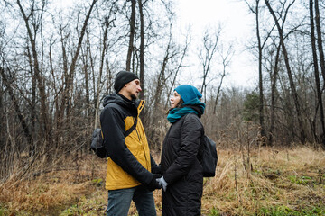 partners sharing serene moment, couple united amid wintery woodland tranquility, two individuals bonding peacefully in open clearing surrounded by dormant trees and muted sky