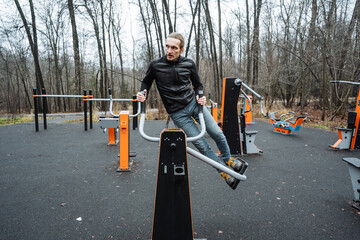 agile park exercise, athletic performer executing energetic leg raise amidst city park setting, skilled athlete demonstrating expressive strength and fluid motion on park gym bar