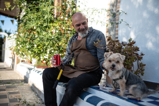 Grandfather and grandson: The 60-year-old man finishes pruning the jasmine and watches his dog.