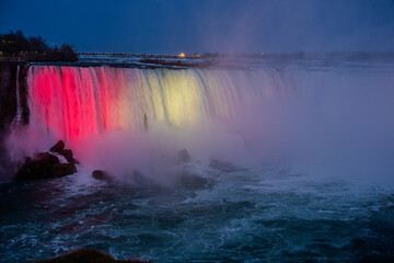 Illuminated waterfall at dusk in Niagara Falls with colorful lights and mist