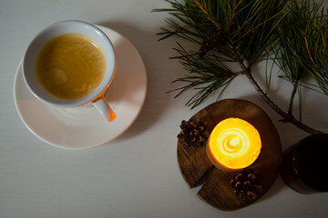 Morning cup of fresh coffee, decor Christmas green tree with a pine cone, wax burning candle....