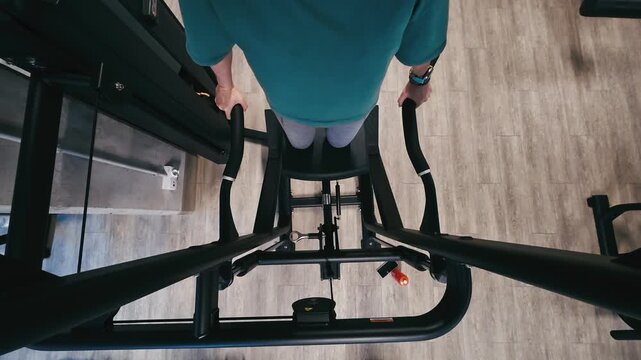 Girl Performs Assisted Dips On Parallel Bars In The Gym With Legs Supported And Viewed From Above