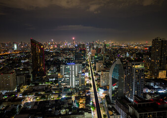 Aerial drone view of Bangkok city skyline with illuminated buildings and traffic at night, Thailand