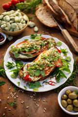 Broad bean spread sandwiches with and grilled goat cheese sprinkled with roasted sunflower seeds and fresh mint on a ceramic plate,  top view