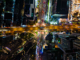 Aerial top view of busy intersection in Bangkok, Thailand, showing heavy traffic, illuminated...