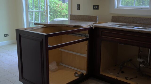 Removal of the old kitchen countertop during a home renovation project. The worker lifts and detaches the laminate counter, preparing for new installation.
