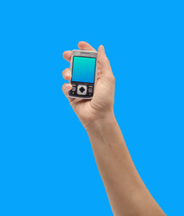 Hand holds retro mobile phone against vibrant blue background, showcasing vintage technology.